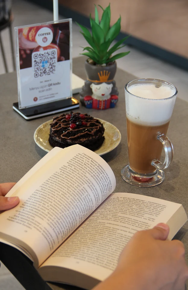 A guest at a café table with a QR menu standee